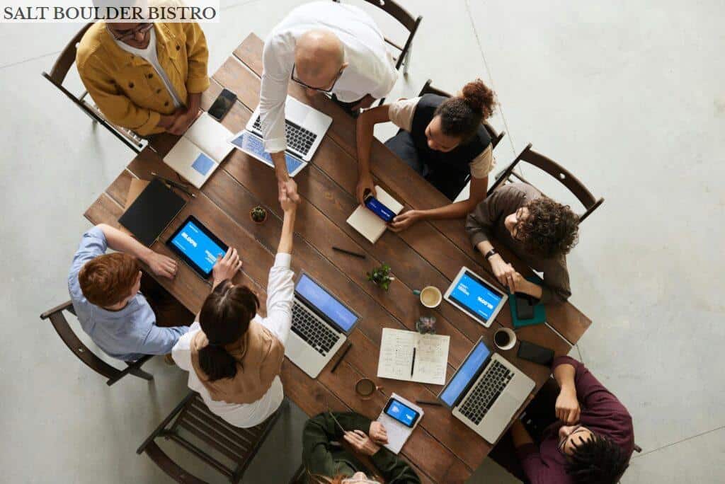 Top view of a diverse team collaborating in an office setting with laptops and tablets, promoting cooperation.